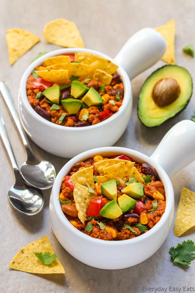 Budget-Friendly Meals: Overhead view of two bowls of Healthy Turkey Chili with spoons on the side on a beige background.