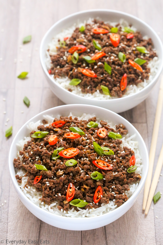 Overhead view of two bowls of Ground Beef Bulgogi with rice on a wooden surface with chopsticks on the side.