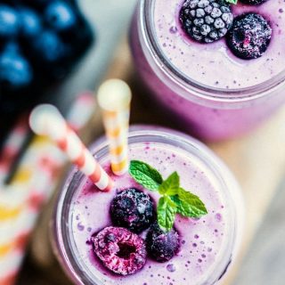 Close-up overhead view of Mixed Berry Protein Shakes in glass jars with straws.